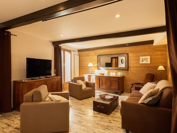 A cozy living room with a flat-screen TV, two sofas, a coffee table, and a wooden wall with a mirror. - 4-room apartment, for 8/9 people, south-facing terrace, pets allowed (Valloire)