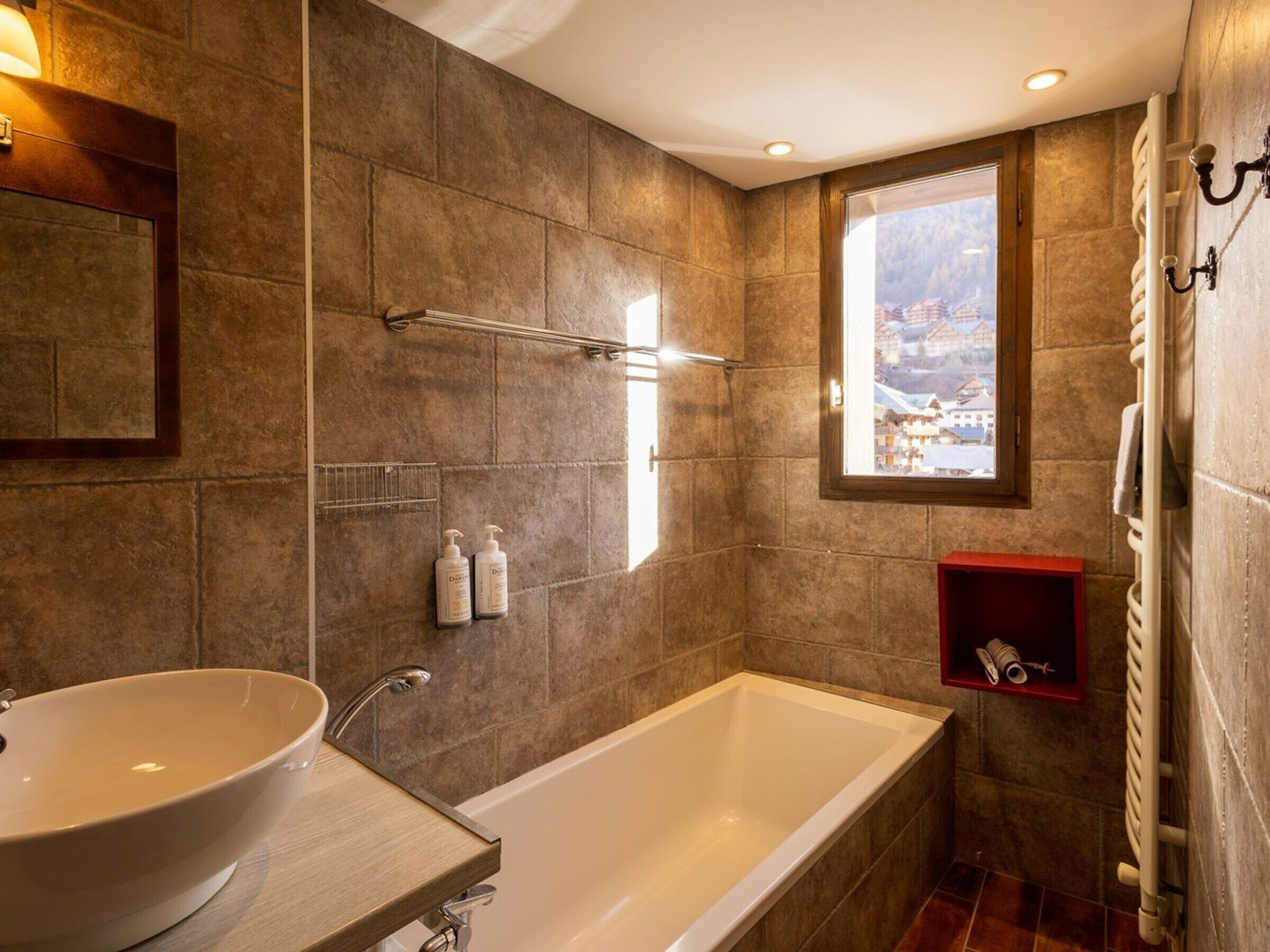 Un baño con una bañera grande, un lavabo y una ventana que ofrece vistas a un paisaje nevado.