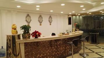 A reception area with a counter, chairs, decorative wall clocks, and a tiled floor.