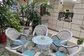 Un patio con mobiliario de mimbre y plantas en macetas.