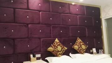 Ein Hotelzimmer mit einem großen, gebürsteten Kopfteil, einem ordentlich bezogenen Bett, einem Nachttisch mit Lampe und einem kleinen Beistelltisch.