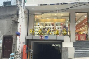 Un edificio con un cartel que dice 'Sheng Long Liquor Store' y un cartel de 'Prohibido Estacionar' debajo.