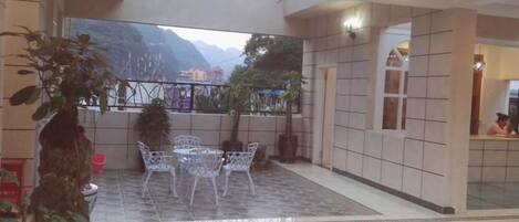 Una habitación de hotel con balcón, un comedor con sillas y vistas a la montaña.