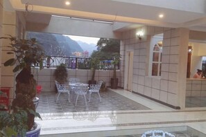 A hotel room with a balcony, a dining area with chairs, and a view of the mountains. - Yanjin Jinzuo Mingdu Hotel (Yanjin)