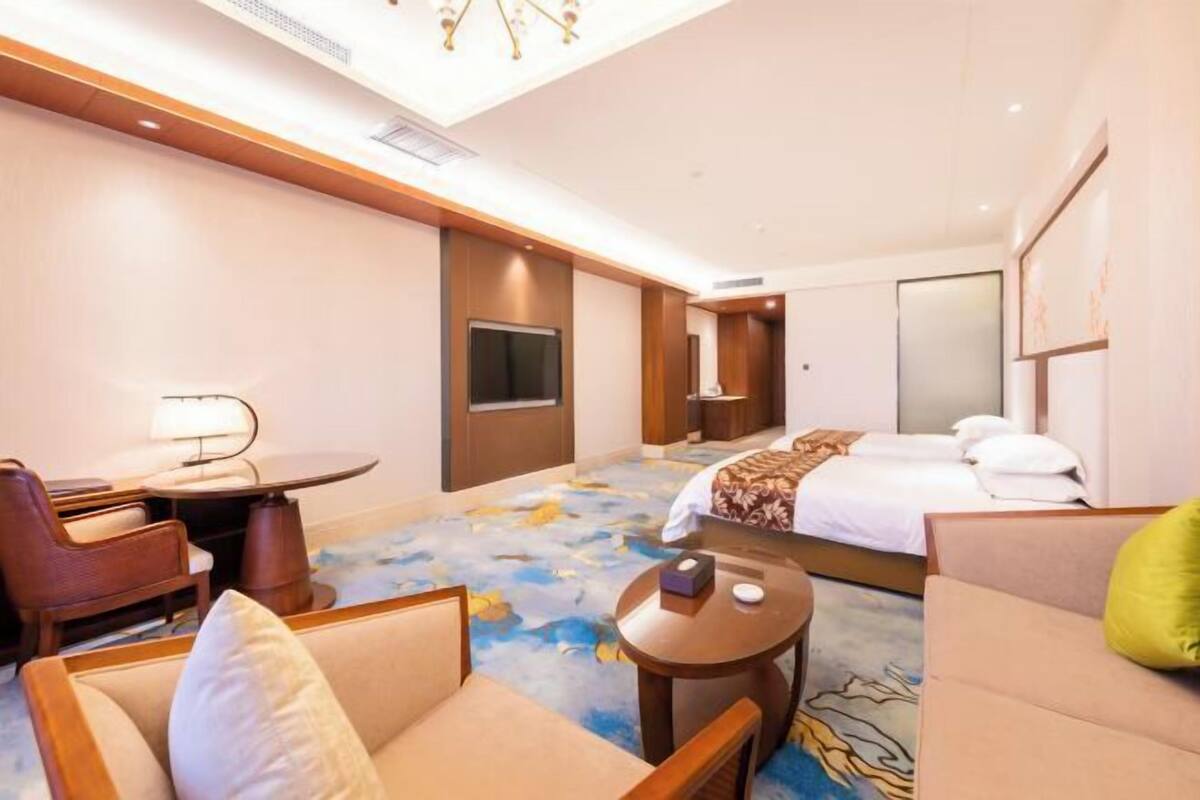 A hotel room with a bed, a desk, a chair, a sofa, and a small table.