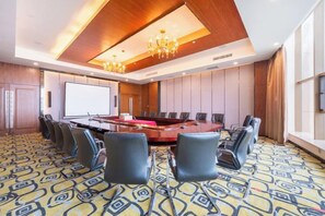 A conference room with a large table, chairs, a projector screen, and a patterned carpet. - Taibai Mountain Wanguo Hotel (Mei County)