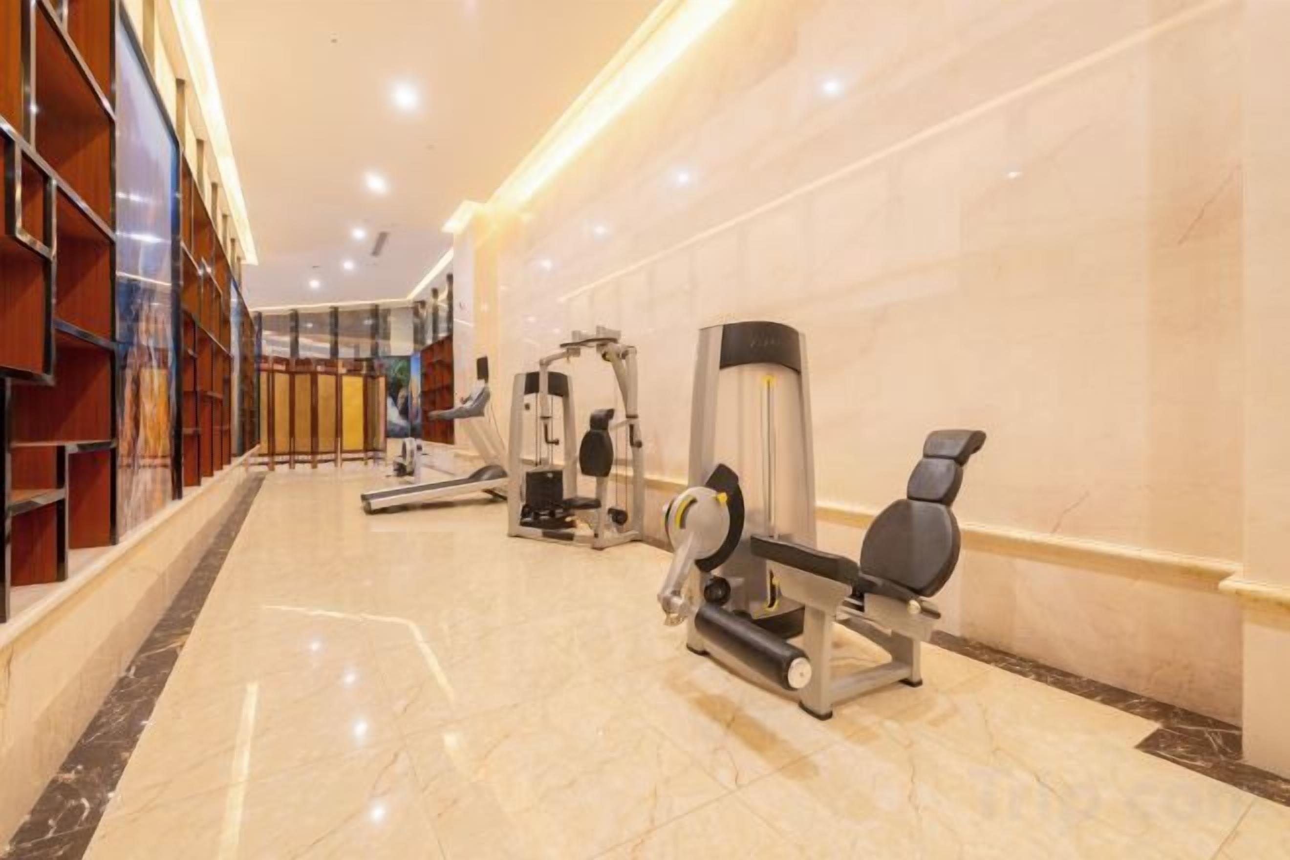 Una palestra con attrezzature per esercizi, tapis roulant e panche per pesi.