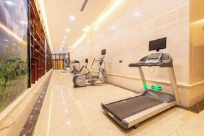 Un gimnasio con cintas de correr y elípticas, una pantalla digital y suelo de mármol.
