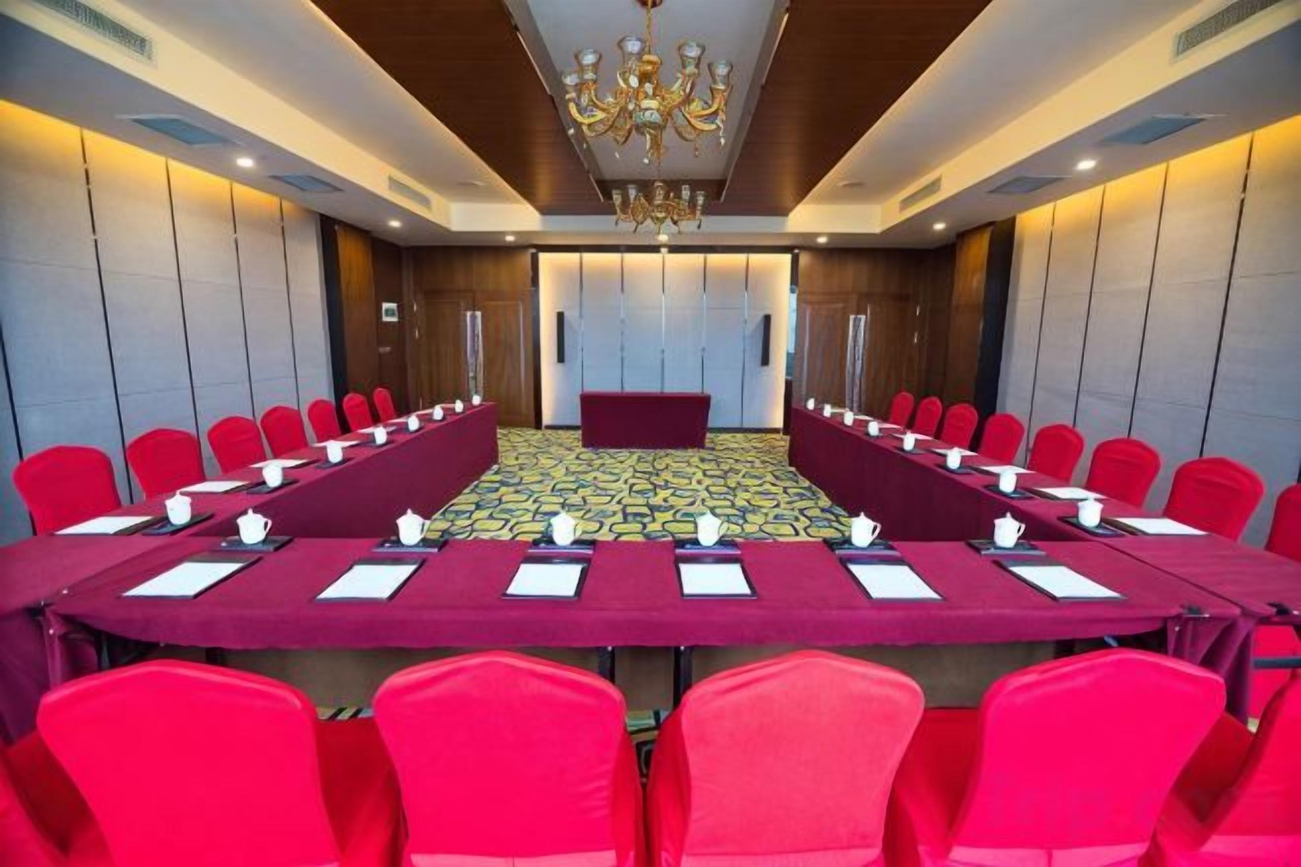 A conference room with a long table and red chairs, equipped with nameplates and water bottles.