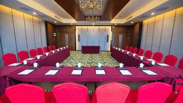 A conference room with a long table and red chairs, equipped with nameplates and water bottles.