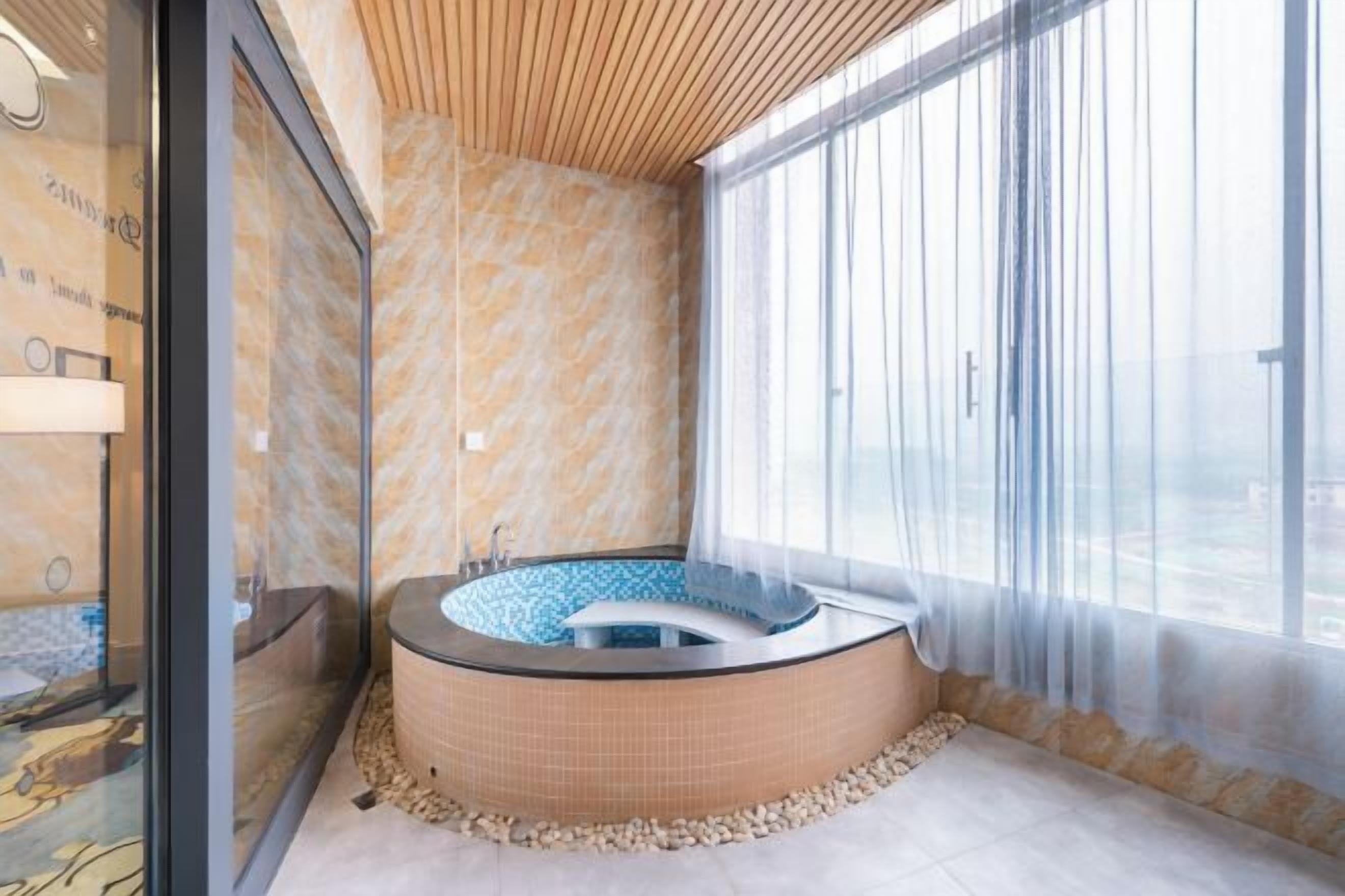 A spa room with a hot tub, a glass wall, and a large window.