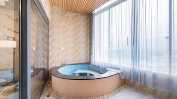 A spa room with a hot tub, a glass wall, and a large window.