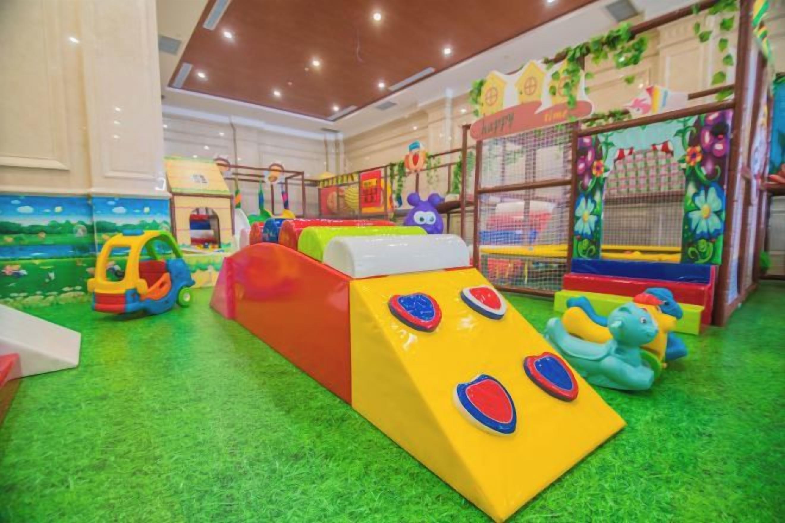 An indoor play area with various play structures and a green carpeted floor.