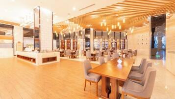 A spacious indoor area with a long wooden table and multiple chairs, surrounded by bookshelves and a fireplace.