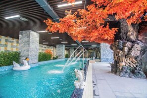 An indoor swimming pool with a decorative tree and a swan float. - Taibai Mountain Wanguo Hotel (Mei County)