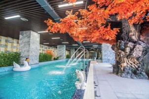 Una piscina interior con un árbol decorativo y un flotador con forma de cisne.