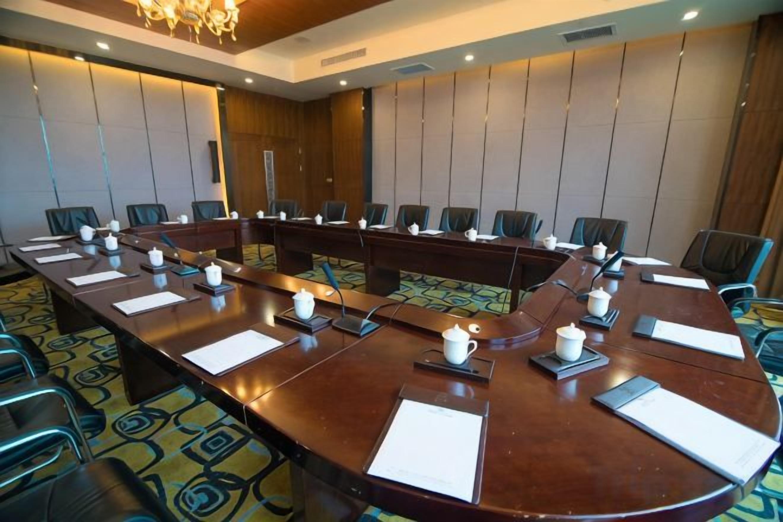 A conference room with a long table, chairs, and a projector screen.