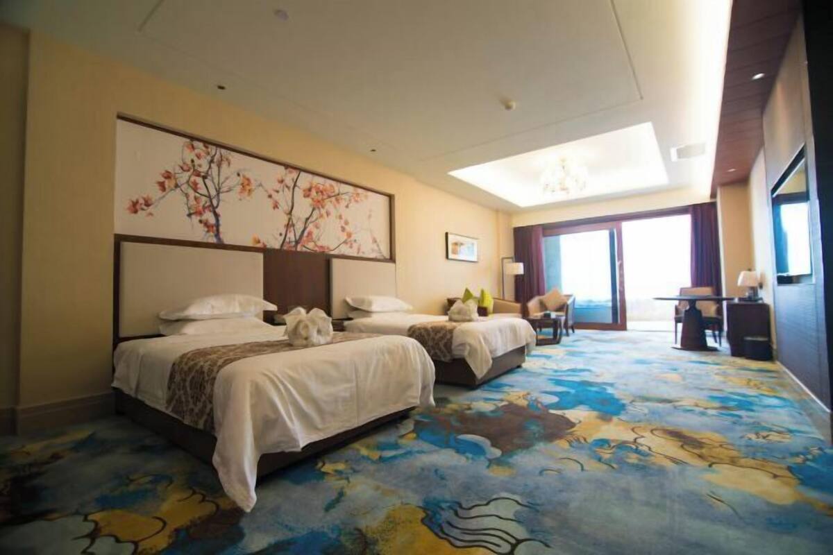 A hotel room with two beds, a large window, and a view of the outdoors.