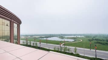 A view from a building's terrace overlooking a road with a river and greenery.