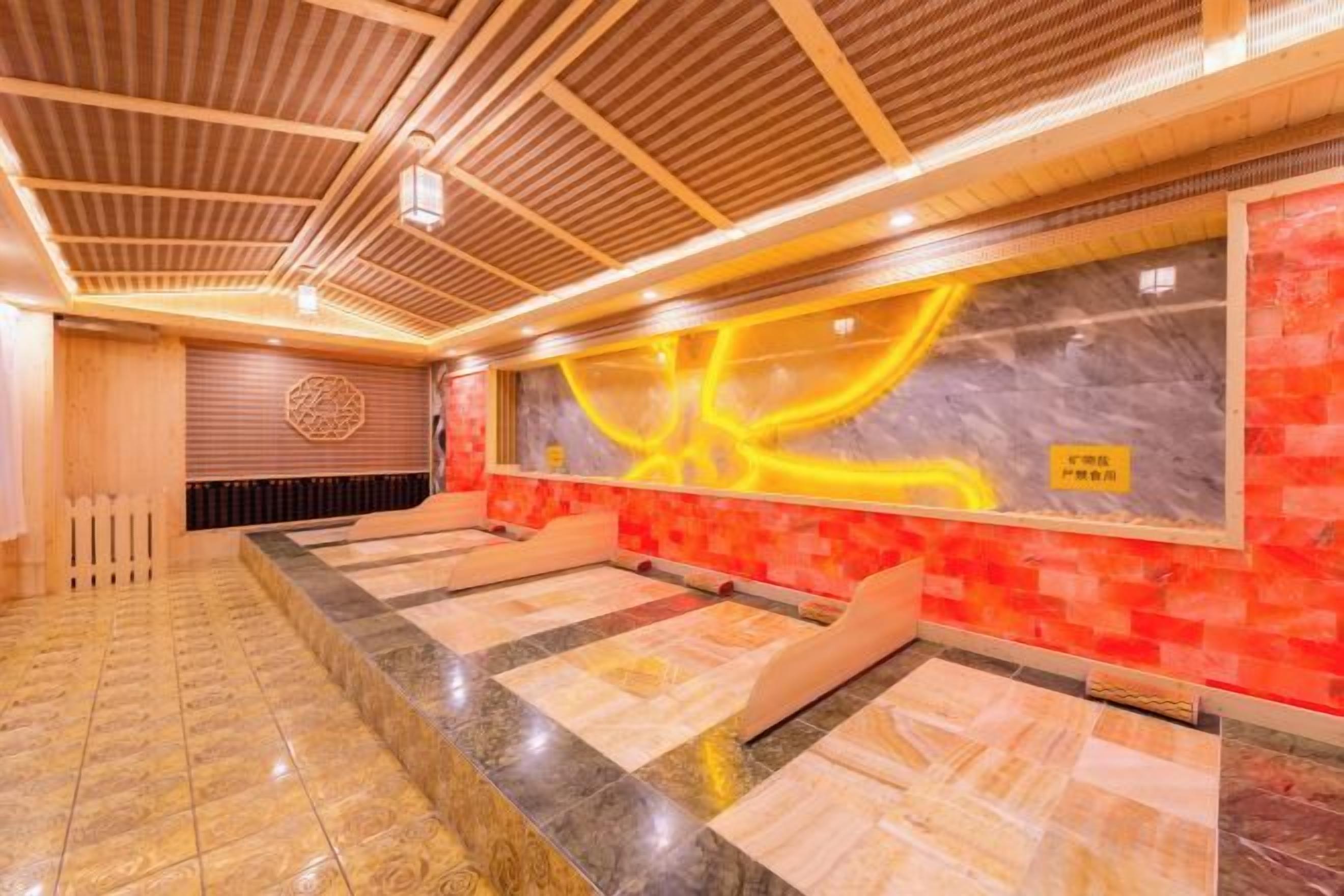 A spa room with a wooden ceiling, a massage table, and a wall with a yellow abstract design.