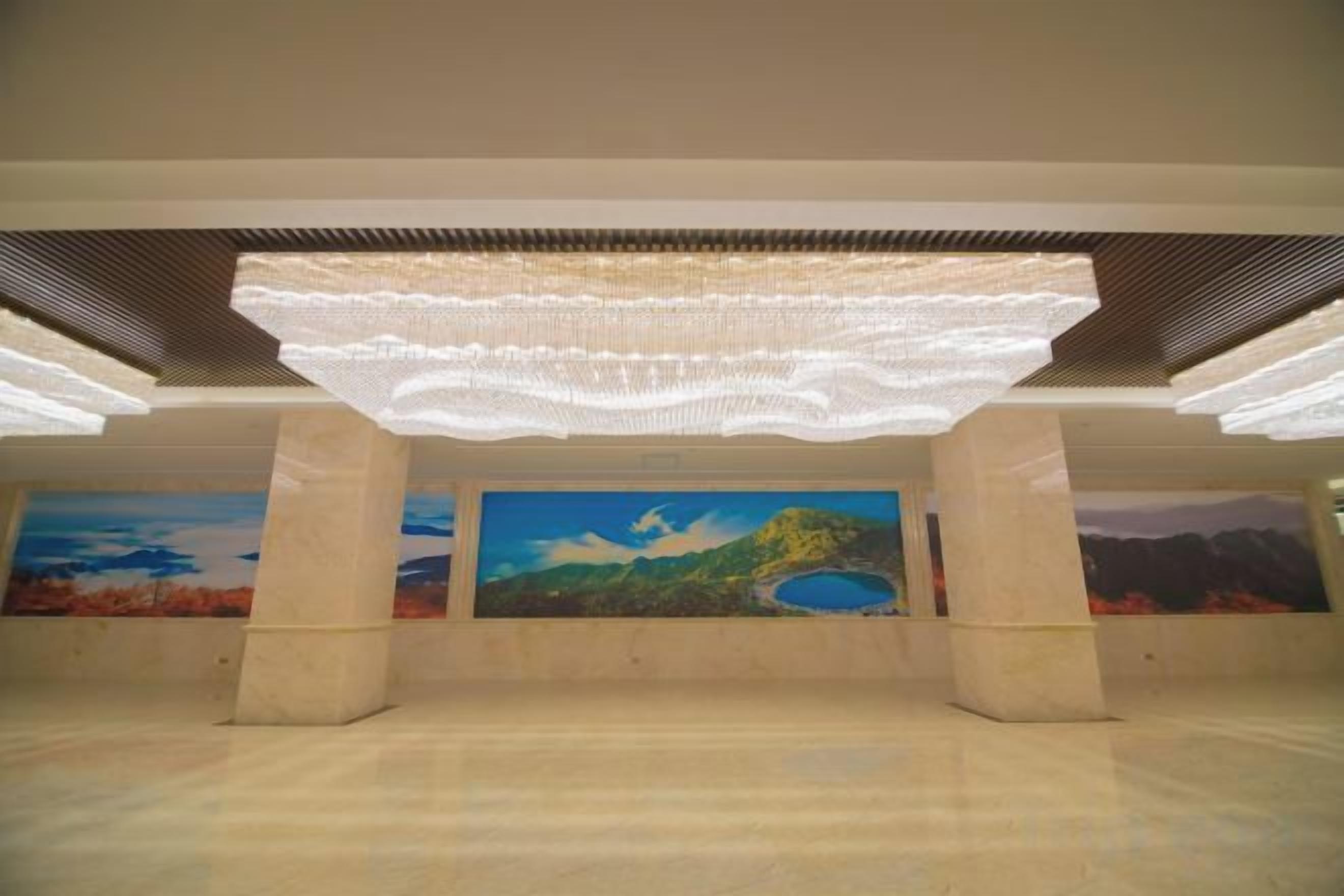 An indoor space with a large open area, a ceiling with a unique light fixture, and a mural on the wall.