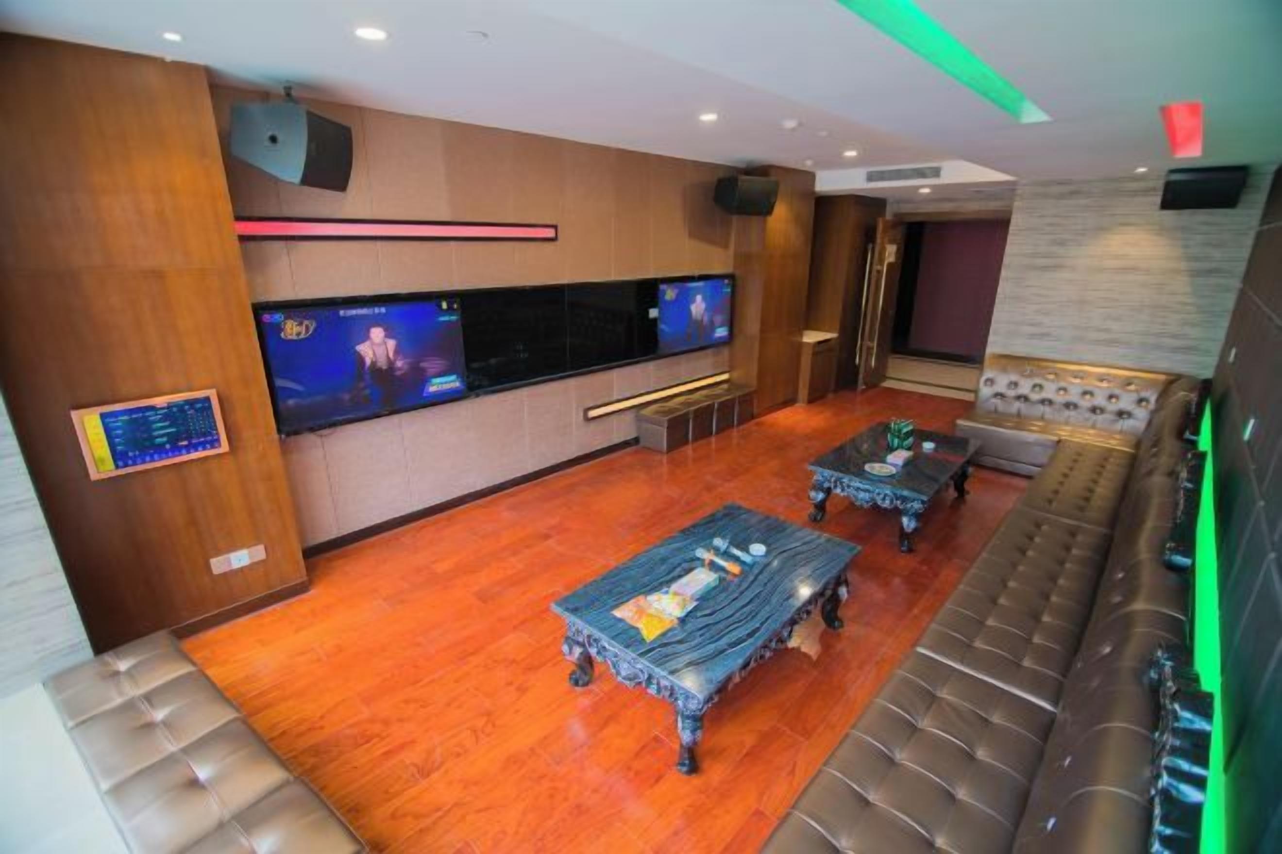 A hotel lobby with a seating area, a television, and a wooden floor.
