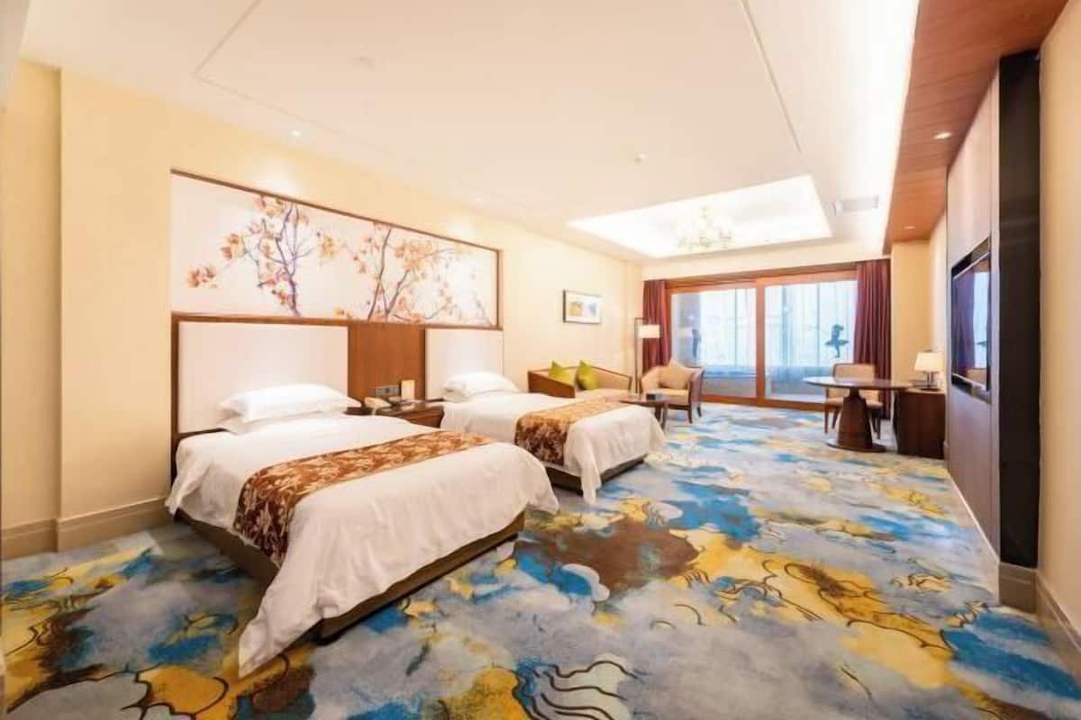 A hotel room with two beds, a large window, and a view of the outside.