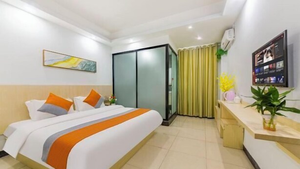 Habitación de hotel con cama, escritorio, televisor y puerta corredera.