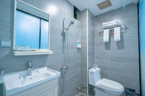 A bathroom with a sink, mirror, shower, and toilet.