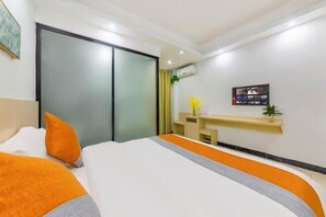 A modern hotel room with a bed, a desk, and a TV.