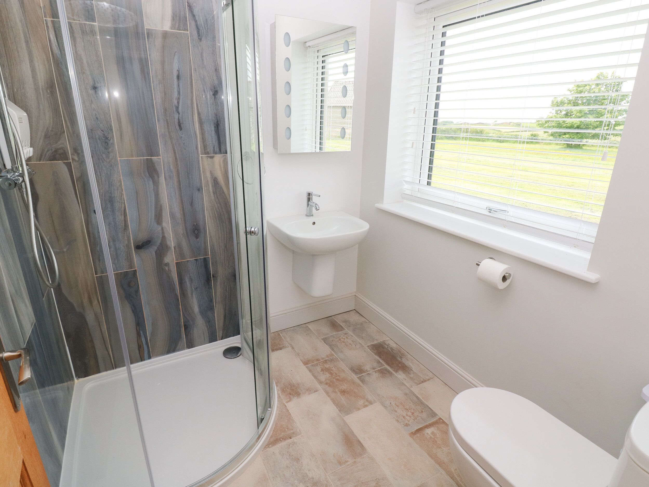 A bathroom with a glass-enclosed shower, a sink, and a toilet.