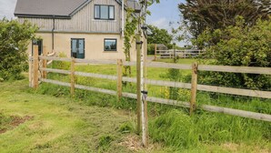 A two-story house with a wooden facade, a front door, and a fenced yard. - Landfall (Pembroke)