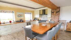 A modern kitchen with a large island, white cabinetry, and a brick accent wall. - Landfall (Pembroke)