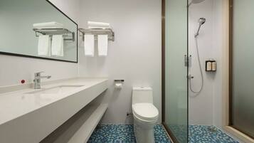 Un baño con lavamanos blanco, espejo, inodoro y ducha.