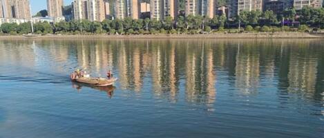 Un río tranquilo con una barca transportando gente, rodeado de edificios altos.