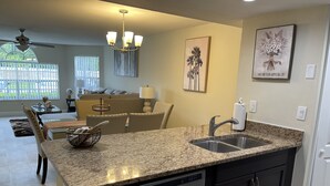 A modern kitchen with granite countertops, stainless steel appliances, and a dining area with a sofa and table. - LOVELY LUXURY APARTMENT CLOSE DISNEY (Kissimmee)