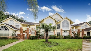 A large, two-story house with a brick facade, multiple windows, and a well-maintained lawn. - LOVELY LUXURY APARTMENT CLOSE DISNEY (Kissimmee)