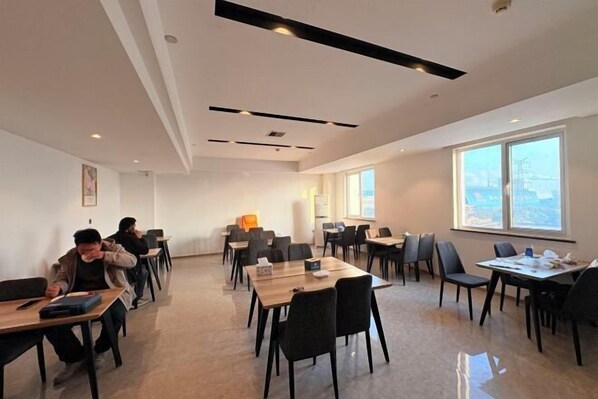 A conference room with tables and chairs, large windows, and a view of the city. - Yahao Selected Hotel (Jinfeng Branch) (Zhangjiagang)