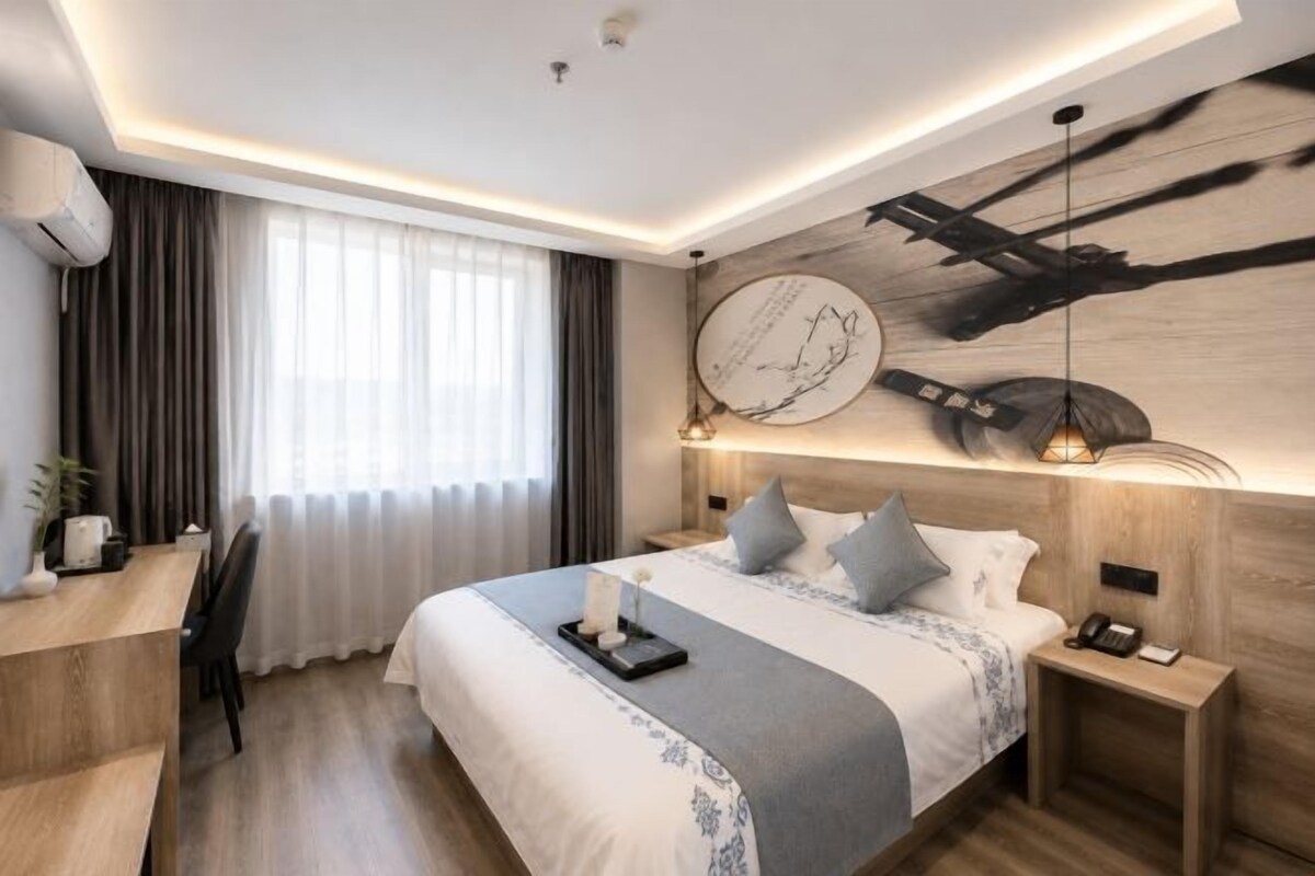 Una habitación de hotel moderna con una cama grande, un escritorio y una obra de arte colgada en la pared.