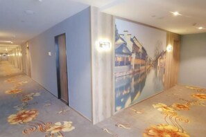 A hotel corridor with a long hallway, doors, and a large mural on the wall. - Yahao Selected Hotel (Jinfeng Branch) (Zhangjiagang)