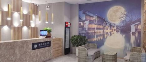 A hotel reception area with a modern design, a reception desk, seating area, and a large wall mural.
