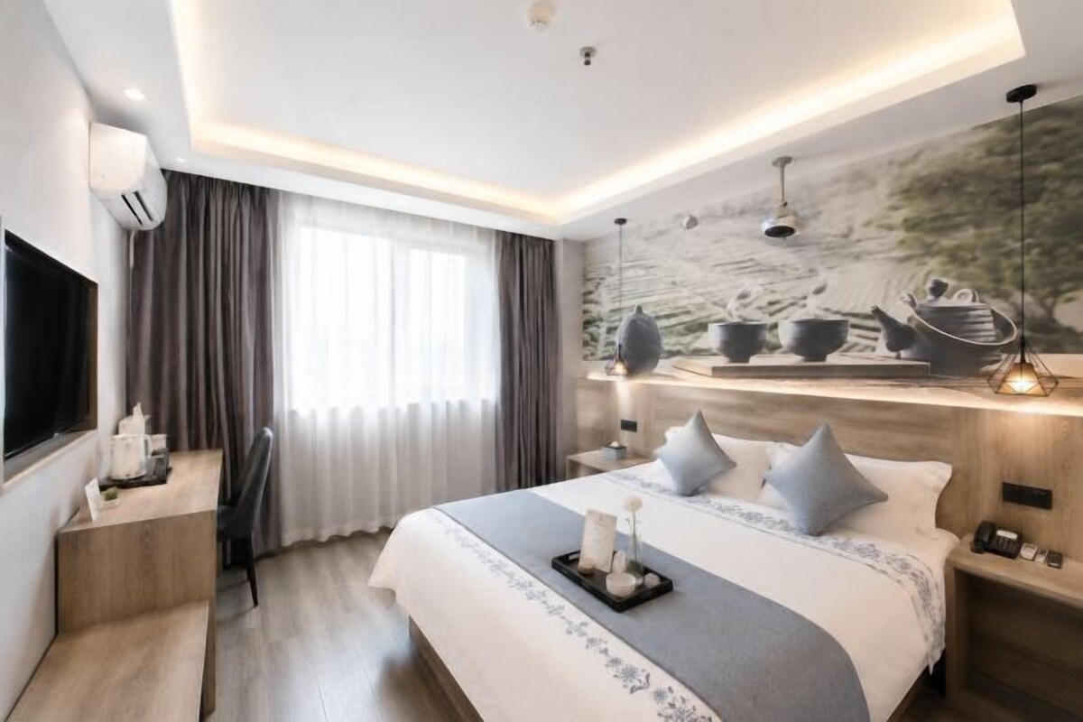 Una habitación de hotel moderna con una cama grande, mesitas de noche, un escritorio y un televisor.
