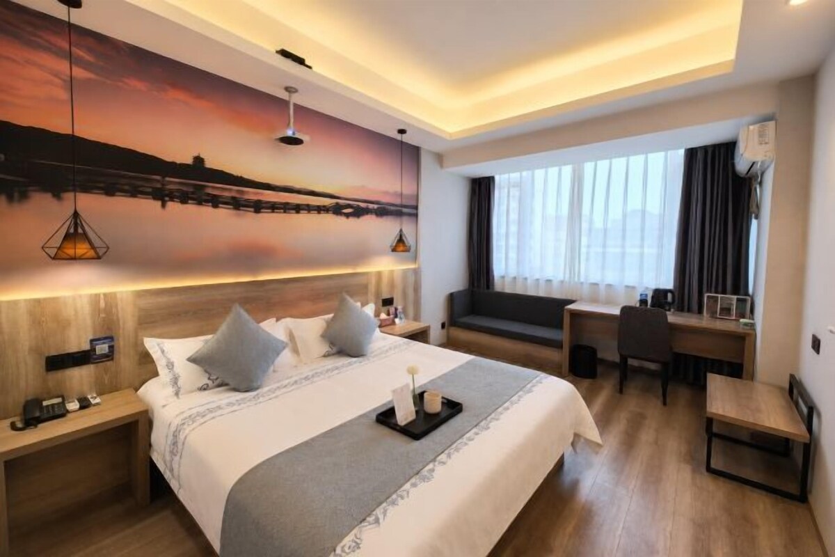 Habitación de hotel moderna con una cama grande, un escritorio, un sofá y vistas a la ciudad.