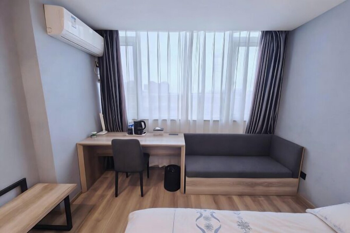 A hotel room with a desk, chair, sofa, and a bed.