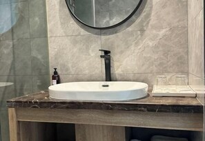 A bathroom with a round mirror, a white sink, and a marble countertop. - Yahao Selected Hotel (Jinfeng Branch) (Zhangjiagang)