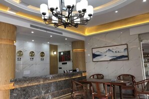 A hotel lobby with a marble reception desk, wooden accents, a chandelier, and a framed artwork on the wall. - Jiuhua Airport Hotel (Chizhou)
