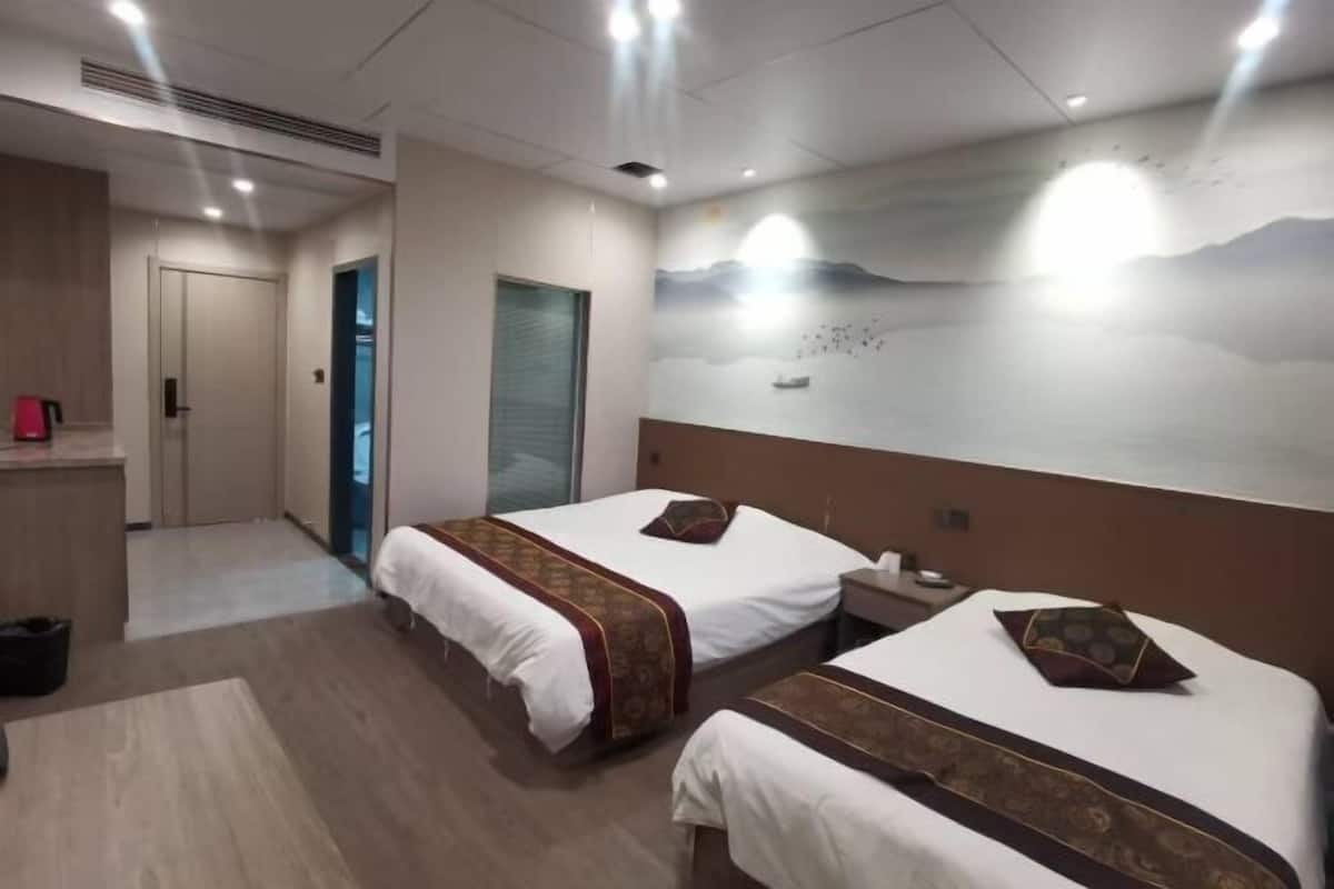 Une chambre d’hôtel avec deux lits, une table de chevet, un bureau et une fresque murale.