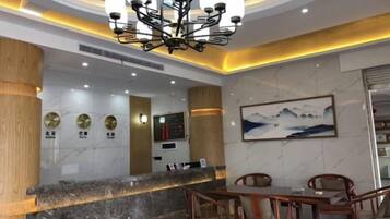 A hotel lobby with a reception desk, seating area, and a chandelier.