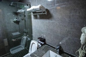 A modern bathroom with a glass-enclosed shower, a white toilet, a sink, and a hairdryer on the counter.