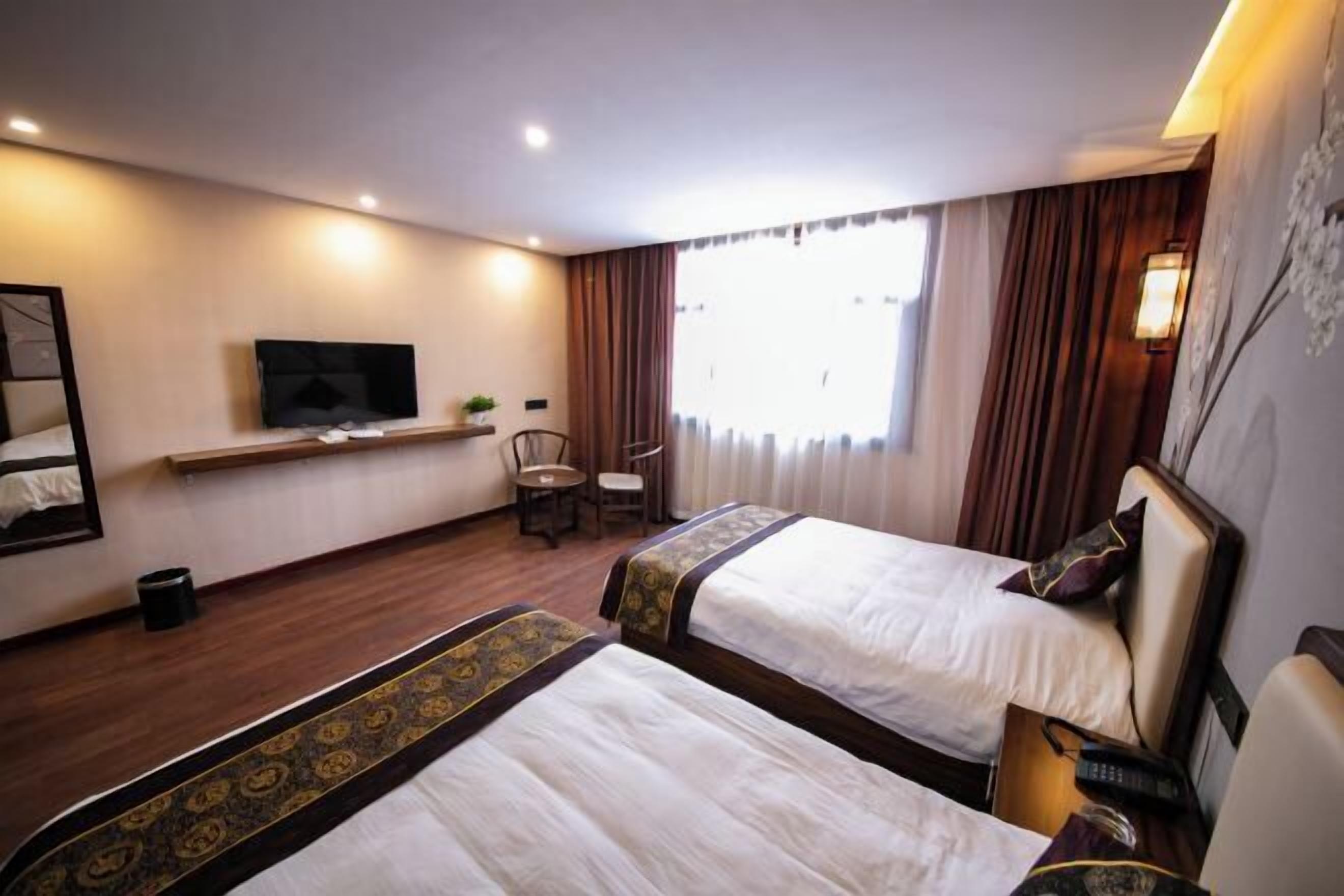 Une chambre d’hôtel avec deux lits, une télévision, un bureau et une chaise.
